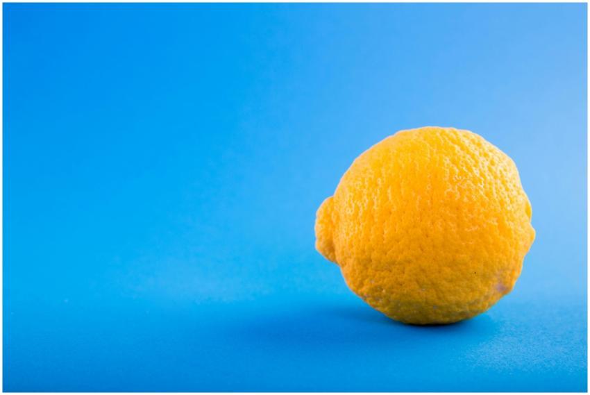 Vivid close-up of a ripe lemon against a bright bl