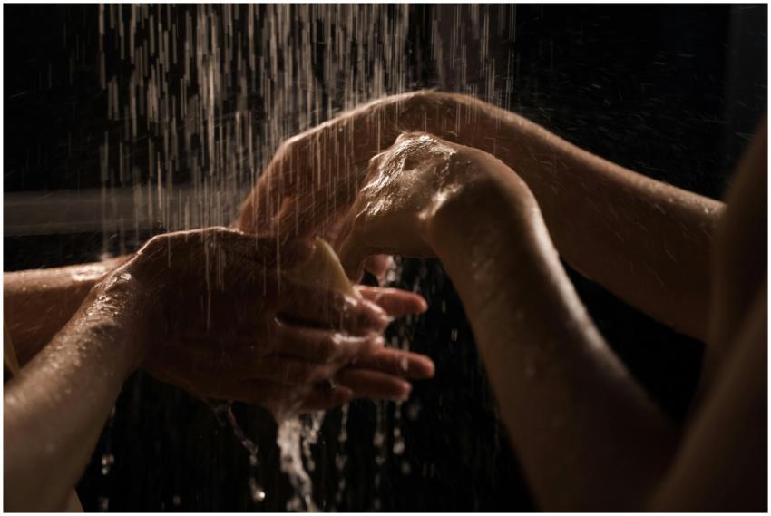 Close-up of hands washing under a shower, emphasiz