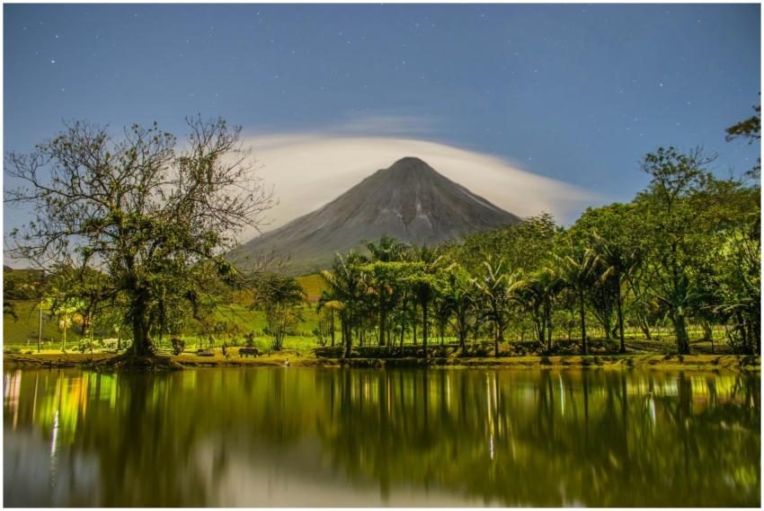Tranquil night scene with a volcano reflected in a