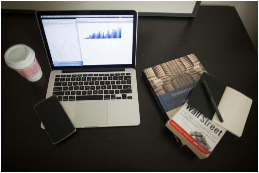 Top view of a desk with laptop, charts, books, and
