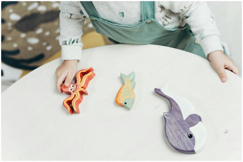 A young child interacts with colorful wooden anima