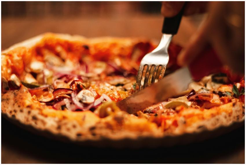 Close-up of a tasty pizza being sliced, featuring