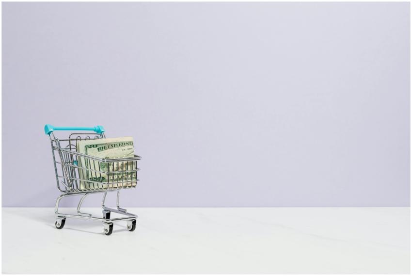 Shopping cart filled with cash on a plain backgrou