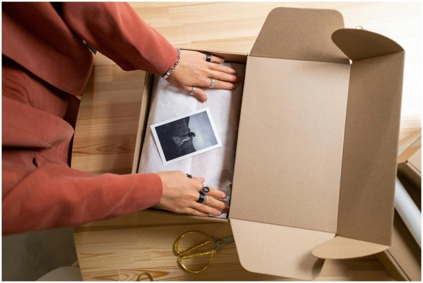 Hands arranging items in a cardboard box with a ph