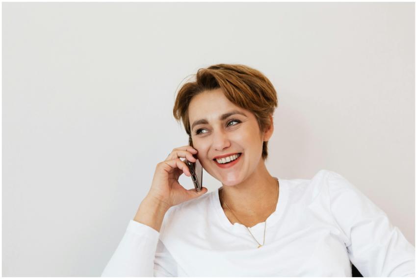 A smiling woman with short hair talking on a phone