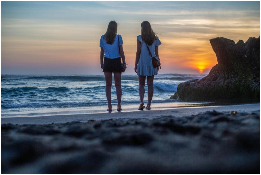 Two women enjoying a serene sunset on a beach in B