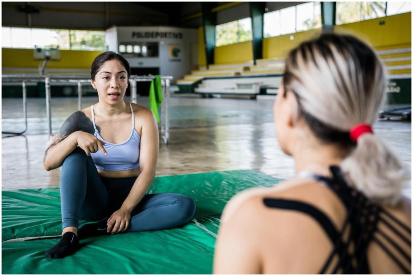 Two women discussing fitness routines indoors, in