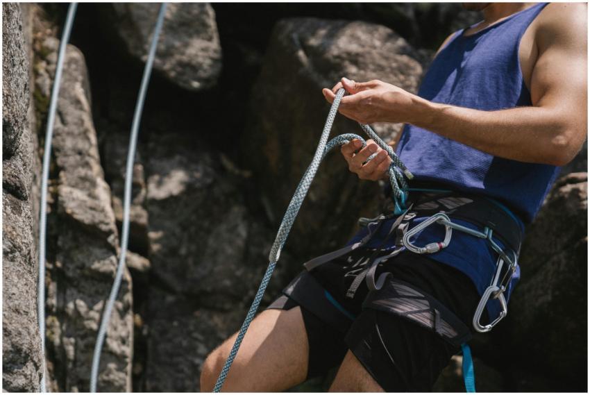 Man in blue shirt rock climbing, focusing on secur