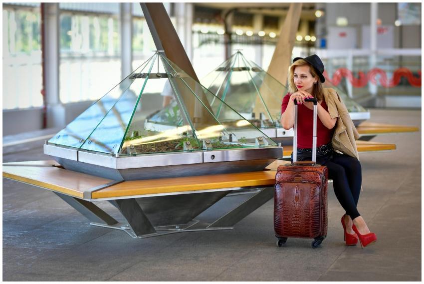 Fashionable woman with luggage sitting in a modern