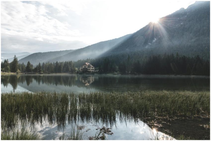 Peaceful lake view with house, mountains, and fore