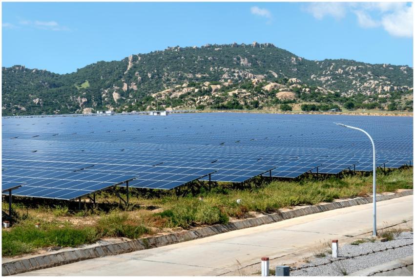 A vast solar farm set against a mountainous landsc