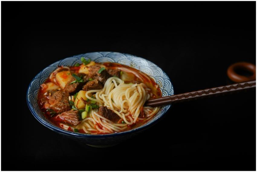 A savory bowl of Asian noodle soup with beef and v