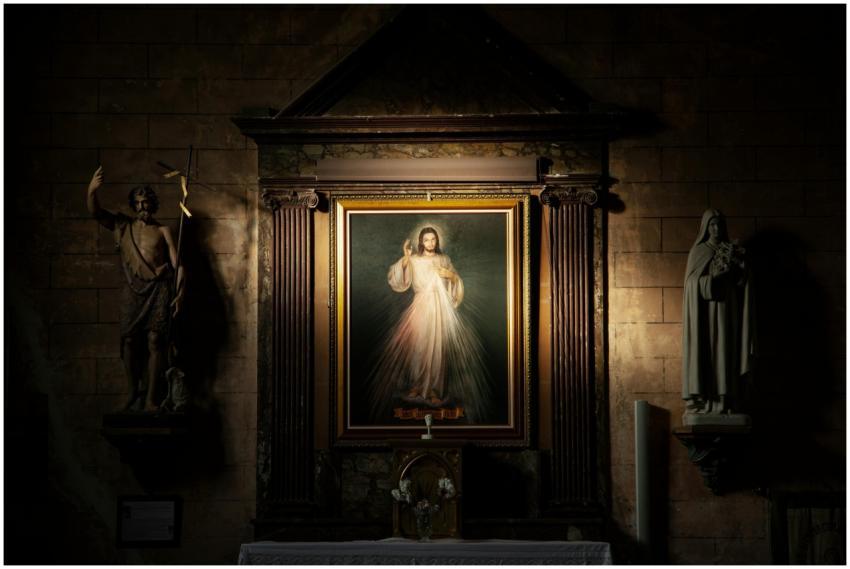 A framed religious portrait flanked by statues ins