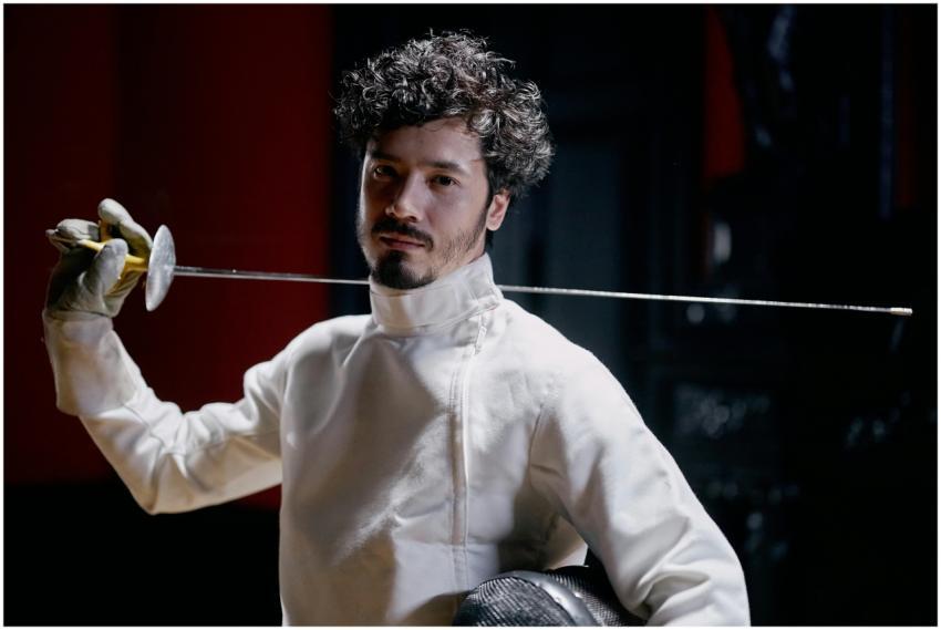 Confident male fencer posing in full fencing gear