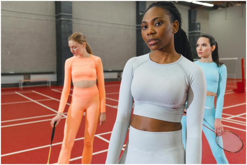 Three women in colorful activewear posing with rac
