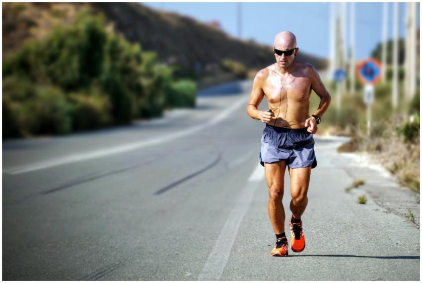 A determined jogger runs on a sunlit road in Crete