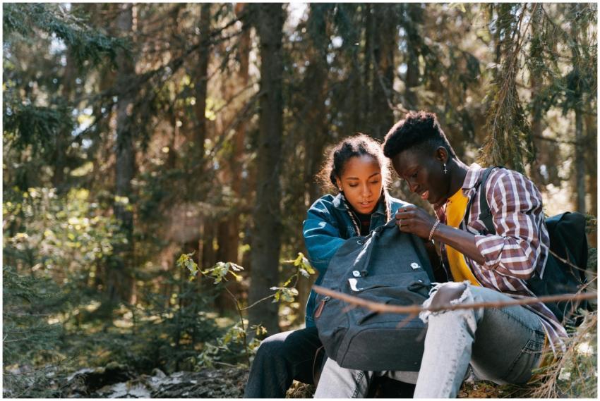 A young couple examining their backpack in a lush