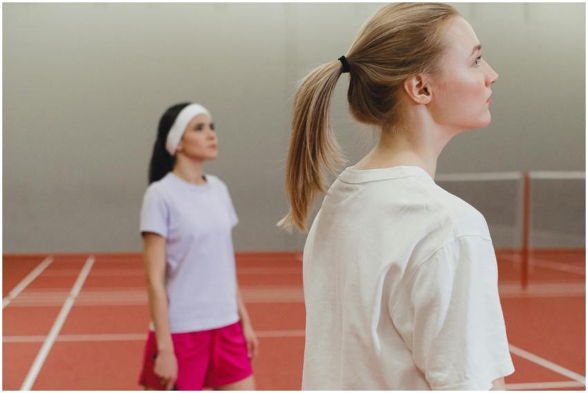 Two women engaged in a badminton match on an indoo