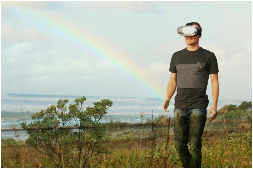 Man using VR headset walks in nature under a rainb