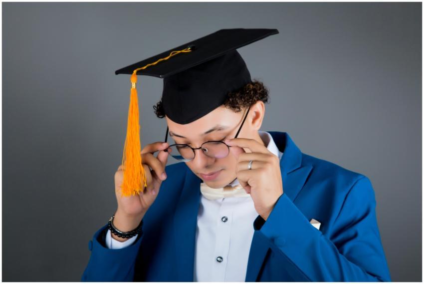Portrait of a young man in a graduation cap adjust