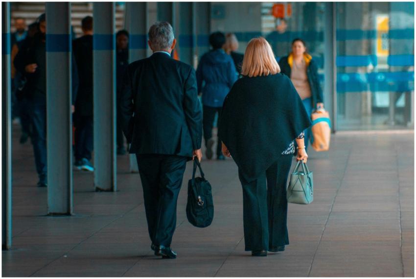 A man and a woman walking with suitcases in a busy