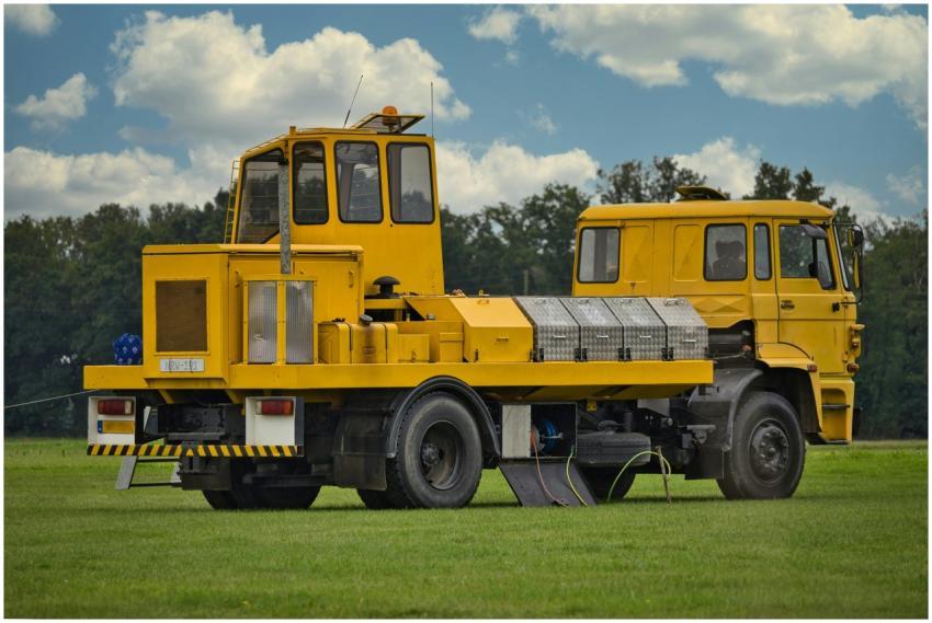 A yellow commercial vehicle parked on a grassy fie
