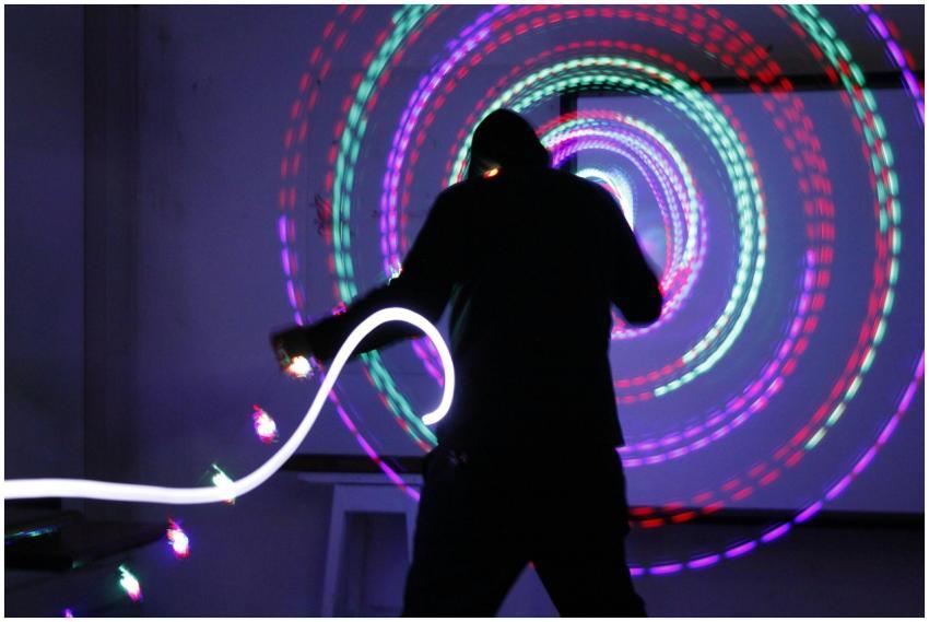 Silhouette of a performer spinning colorful LED po