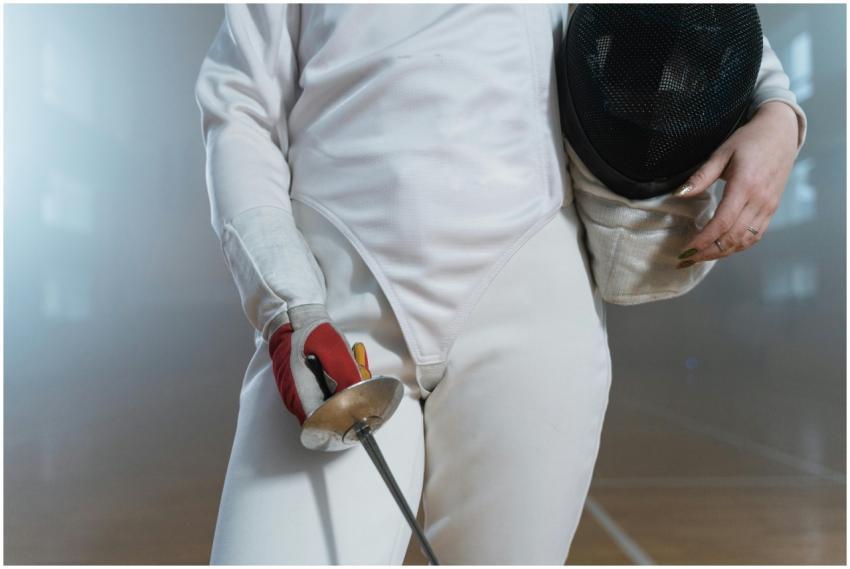 Close-up of a fencer holding an épée and mask indo