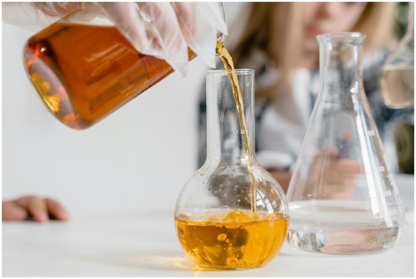 A curious child pours liquid into a flask during a