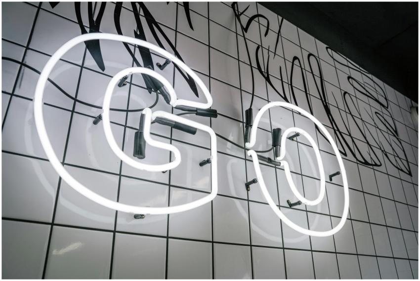 Bright neon sign spelling 'GO' on a white tiled wa