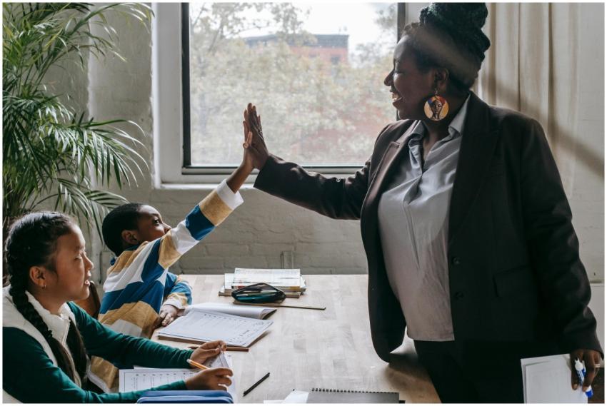 Side view of smiling black boy giving high five to