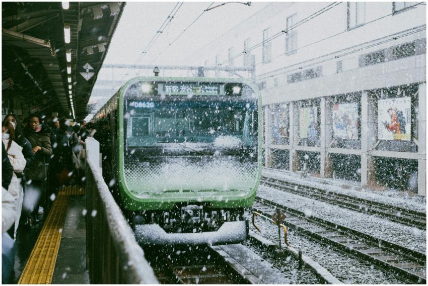 Snow falls at a bustling Shinjuku Station platform