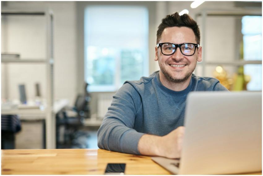 Happy man wearing glasses working remotely on lapt