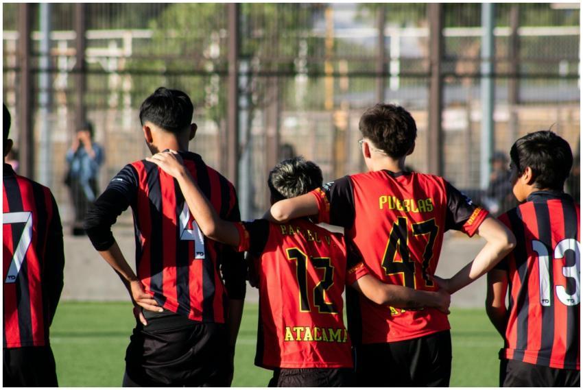 A group of teenagers huddling on a soccer field, s