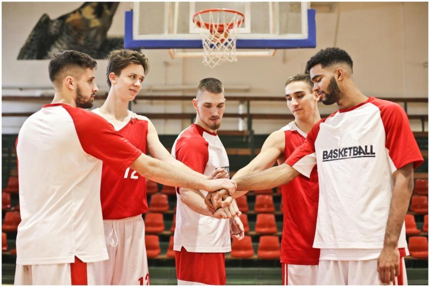 A group of young male basketball players huddle in