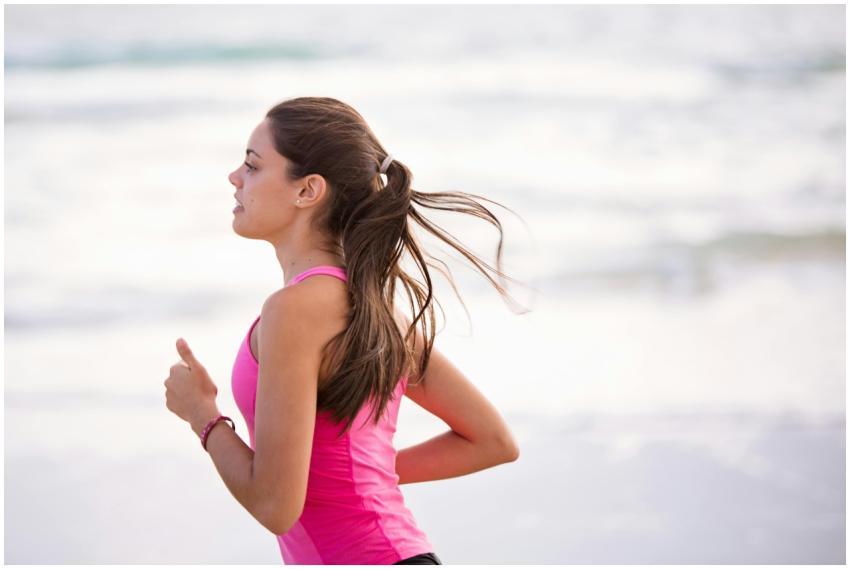 Side view of a young woman jogging on a beach wear