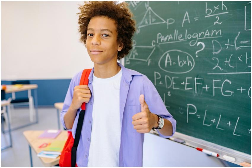 Young student gives thumbs-up in a classroom setti