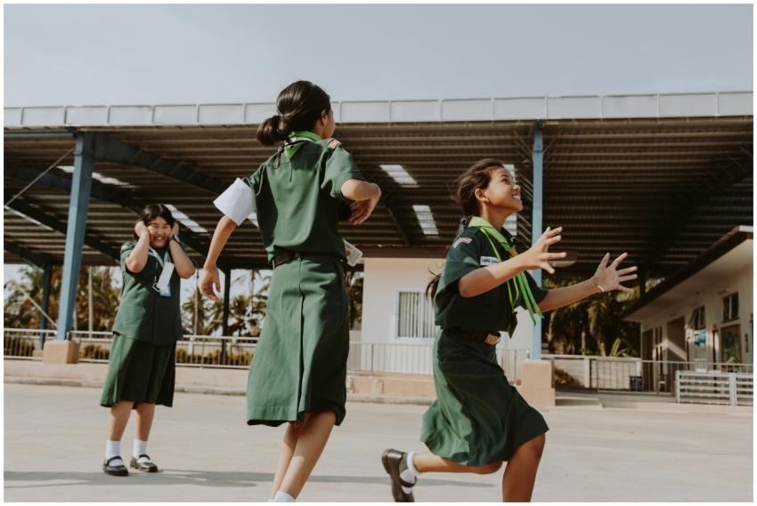 Three girls joyfully playing outside wearing schoo