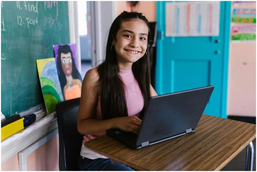 Young student smiling while using a laptop in a cl