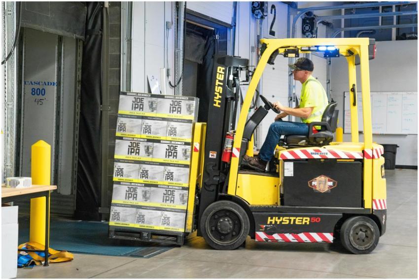 A worker drives a Hyster forklift moving Joe IPA b