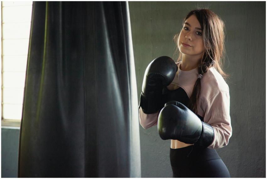 A young woman with boxing gloves trains in an indo