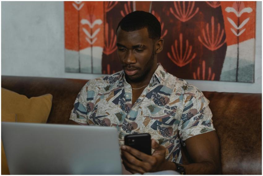 A man sitting on a couch working on a laptop while