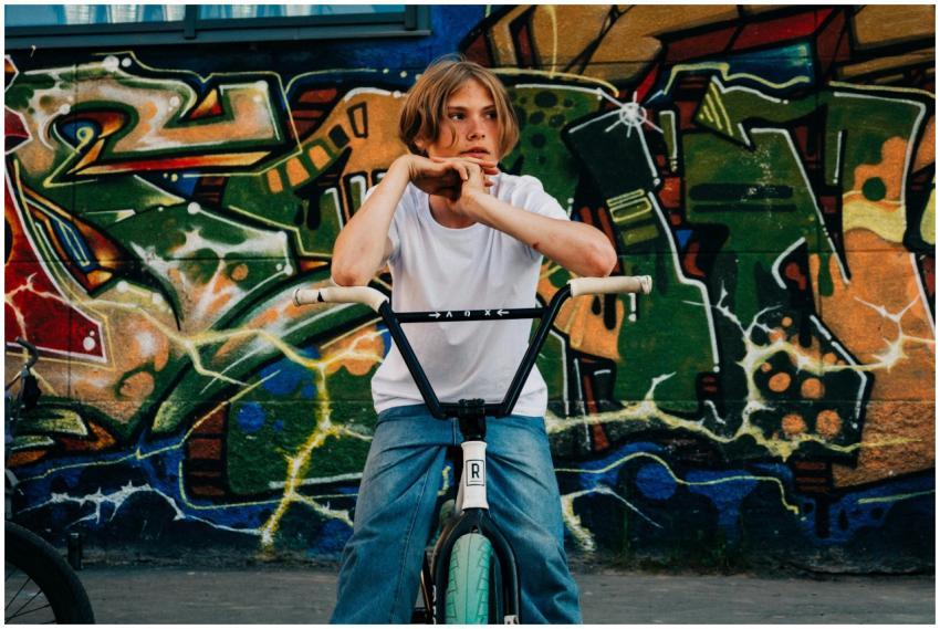 Teenager sits on a bicycle in front of colorful gr