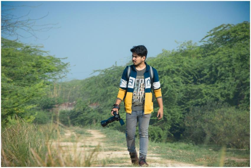 Young man walking on a path through greenery in De