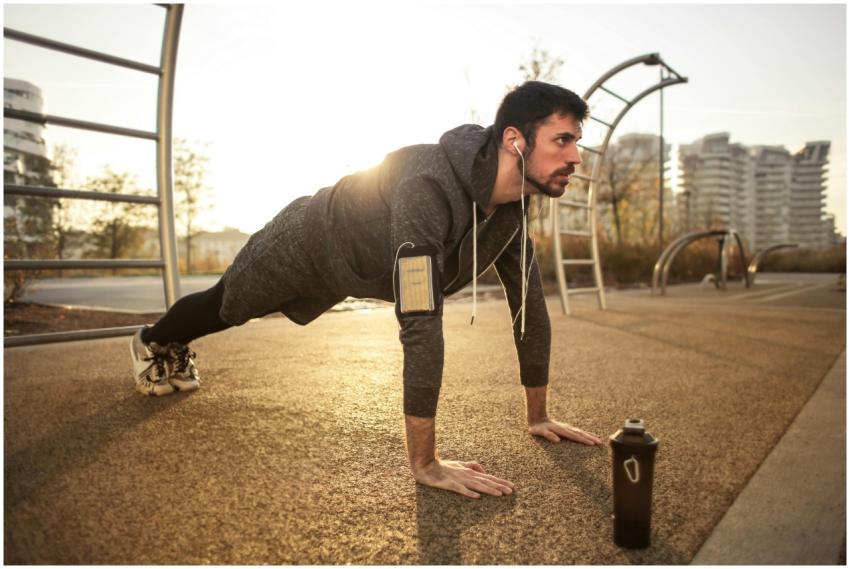 Adult man doing push-ups outdoors with earphones d