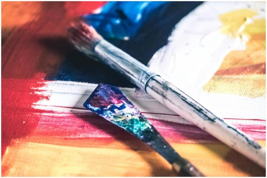 Close-up of colorful paintbrushes on a vibrant can