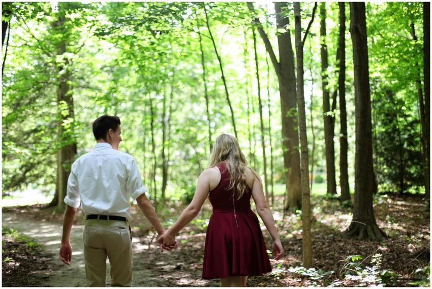 A couple holding hands walking through a sunlit fo