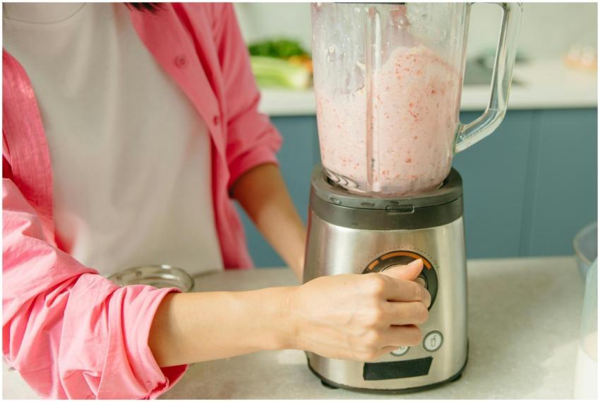 A person in pink attire using a blender to prepare