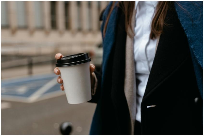 Woman in formal attire holding a takeaway coffee c