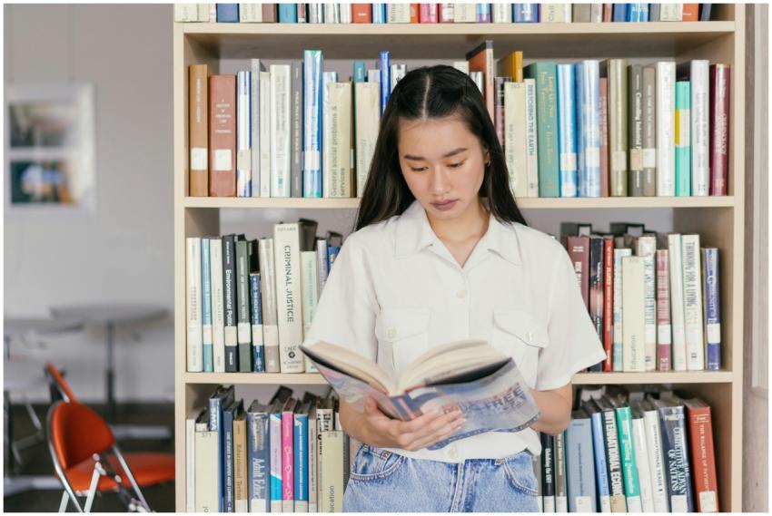 Asian woman reading book in library, engaged in le